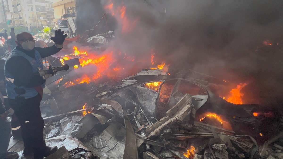 Rescue worker extinguishing burning cars at airstrike site in Beirut