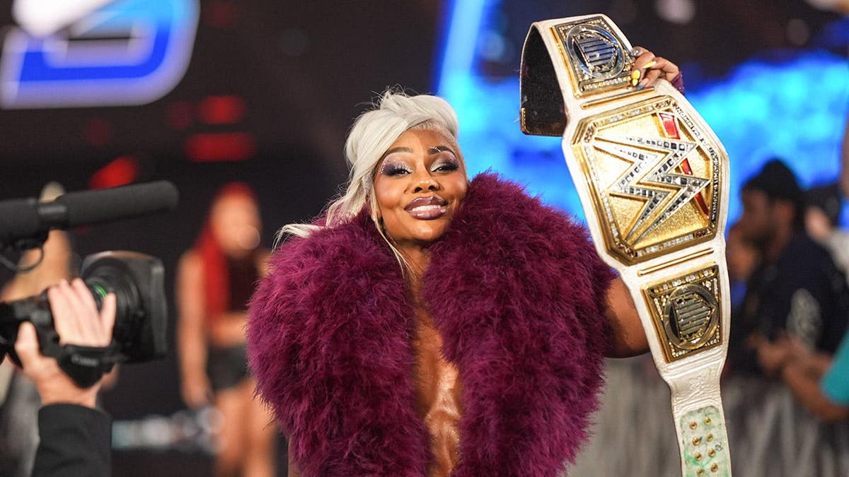 Jade Cargill holding up her championship belt in an arena.