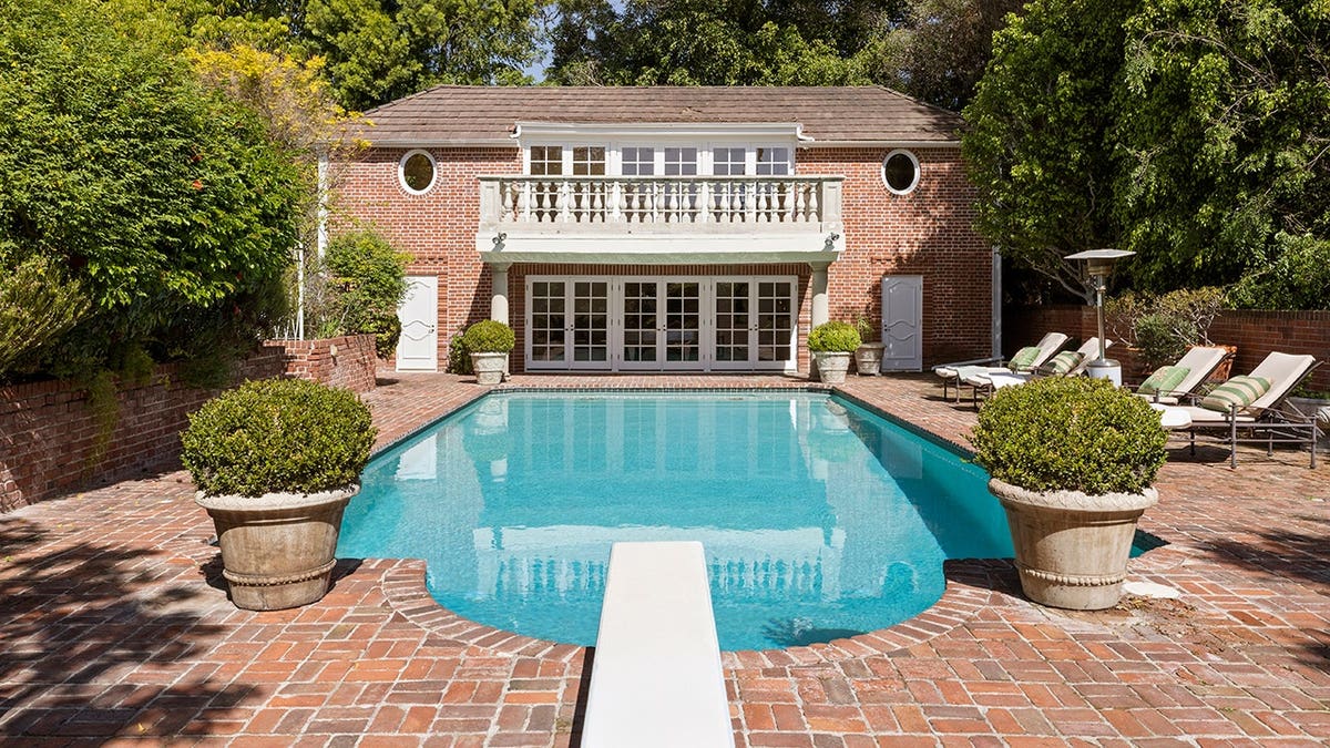 A swimming pool surrounded with brick and a diving board