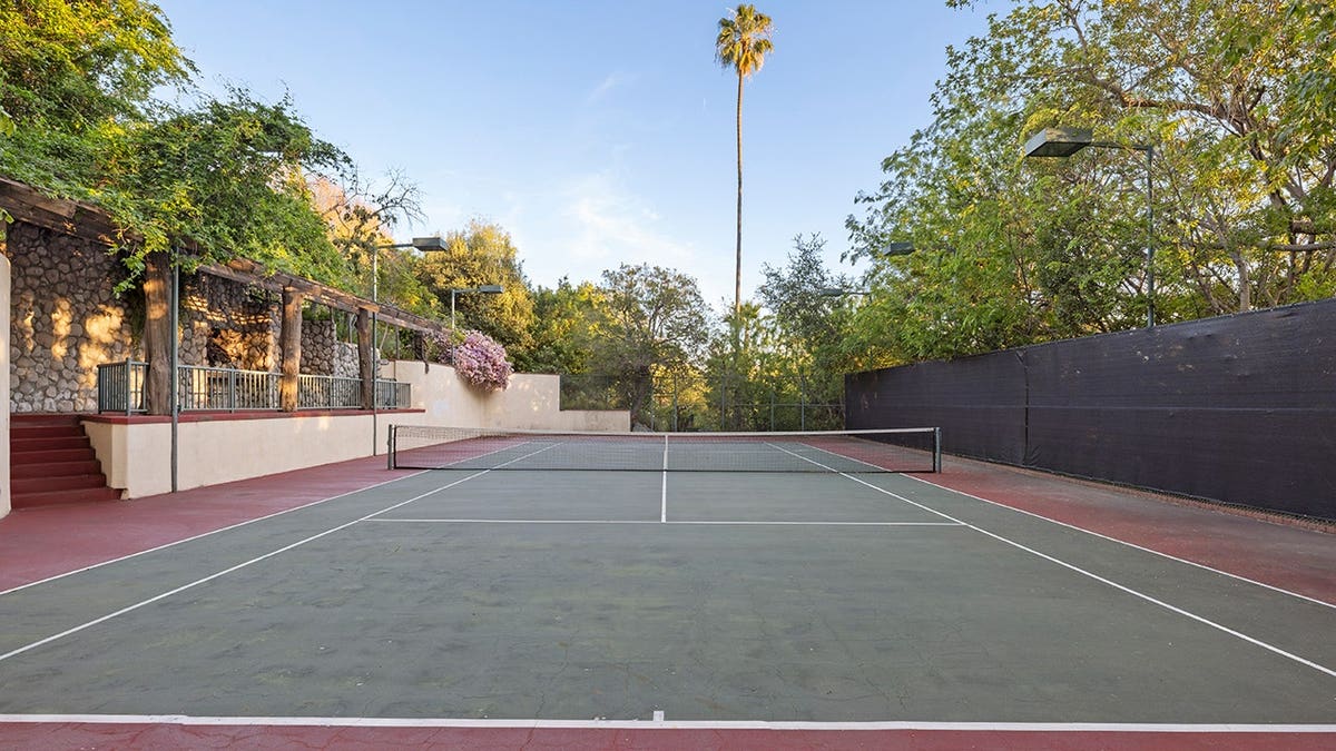 A full-sized tennis court with a cabana