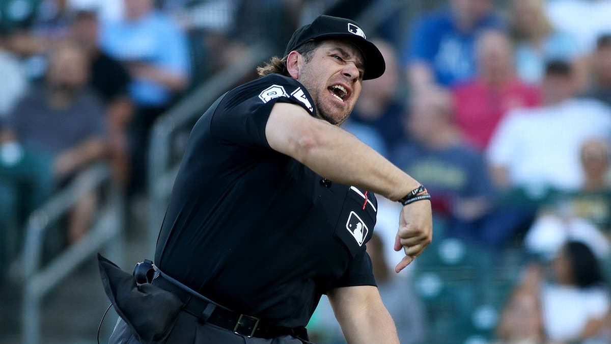 Home plate umpire John Libka throwing out Athletics hitting coach Chris Cron during baseball game.