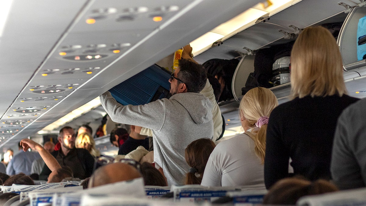Passengers stacking baggage connected  luggage racks wrong  an airplane cabin