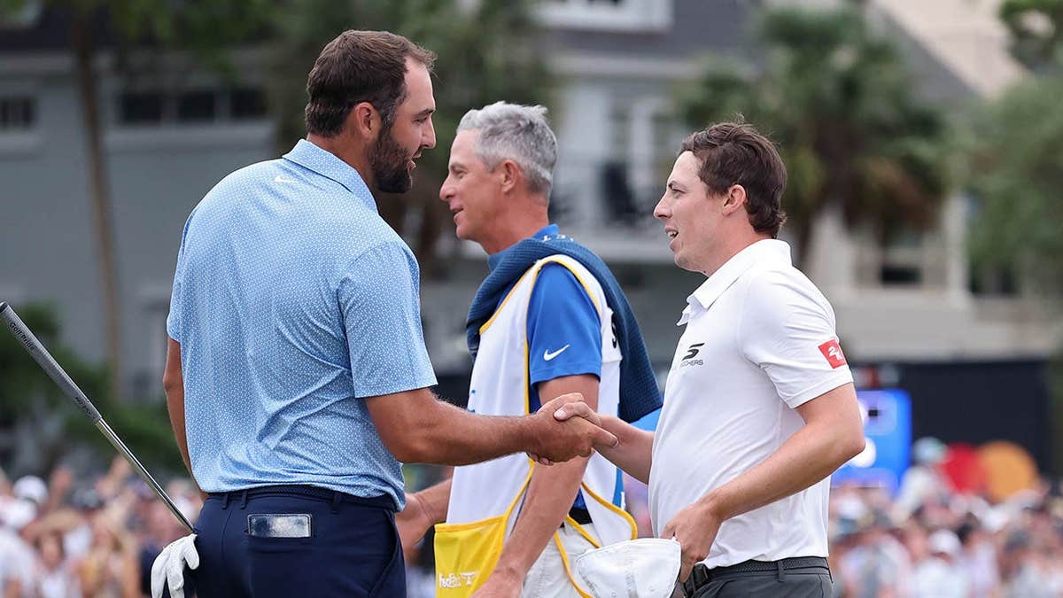 Matthew Fitzpatrick and Scottie Scheffler congratulating each other on a golf course.