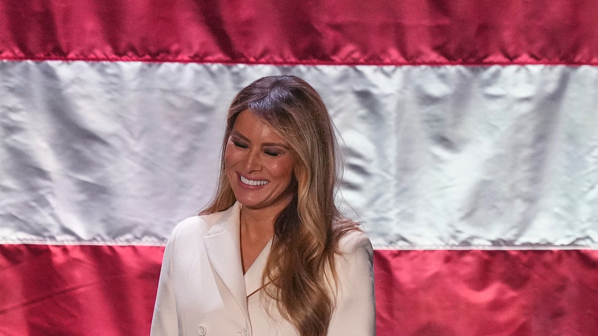 Melania Trump smiling while attending a formal luncheon event.