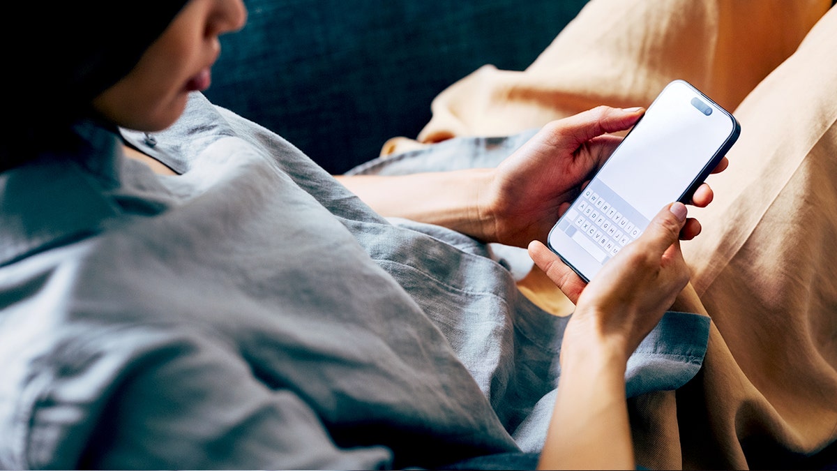 Uma mulher descansa usando um smartphone com teclado na tela.
