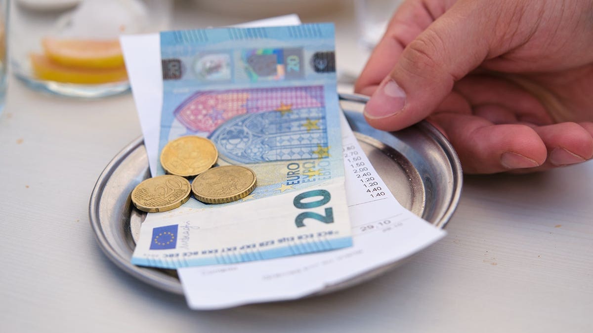 Hand returning metal bill tray with change on bar table