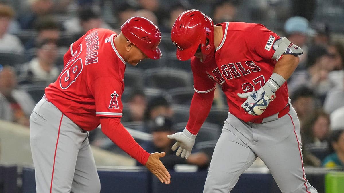 Mike Trout celebrating with Angels third base coach Keith Johnson on baseball field