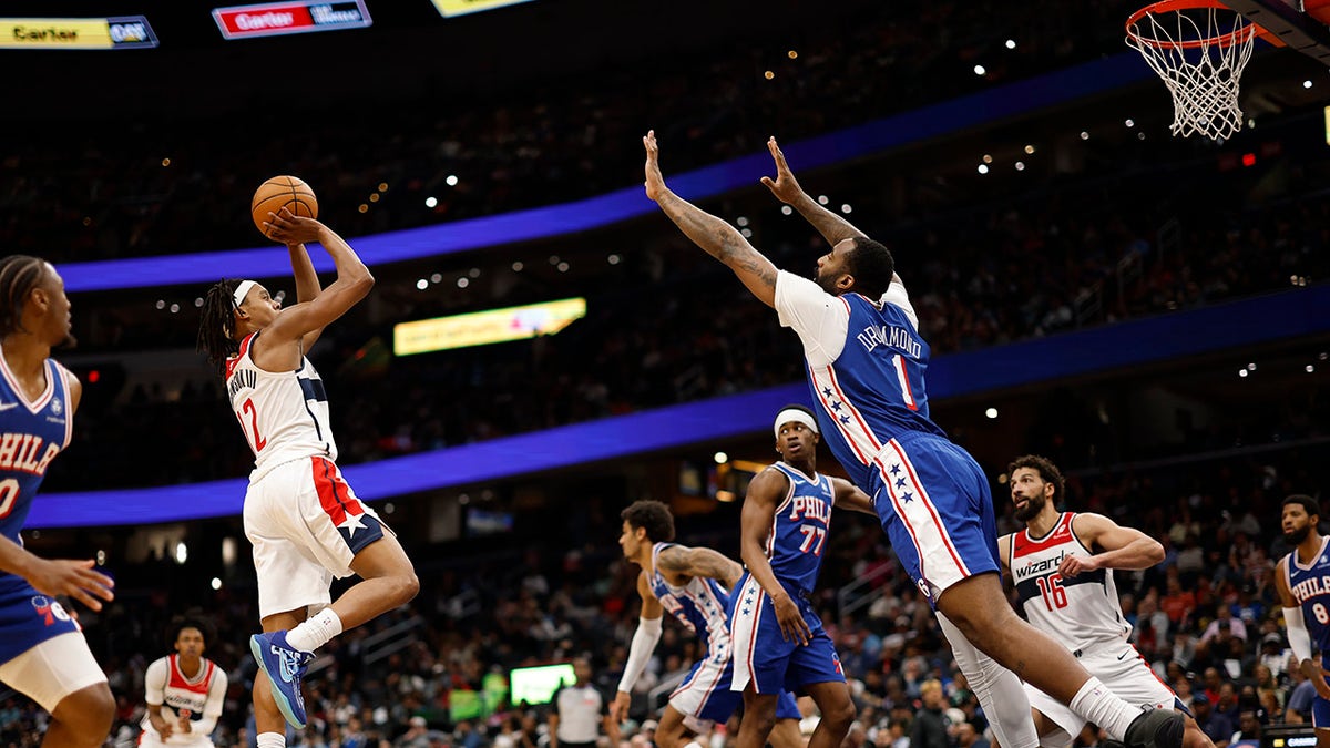 El guardia de los Washington Wizards, Trey Johnson, dispara sobre el centro de los Philadelphia 76ers, Andre Drummond, en Capital One Arena.