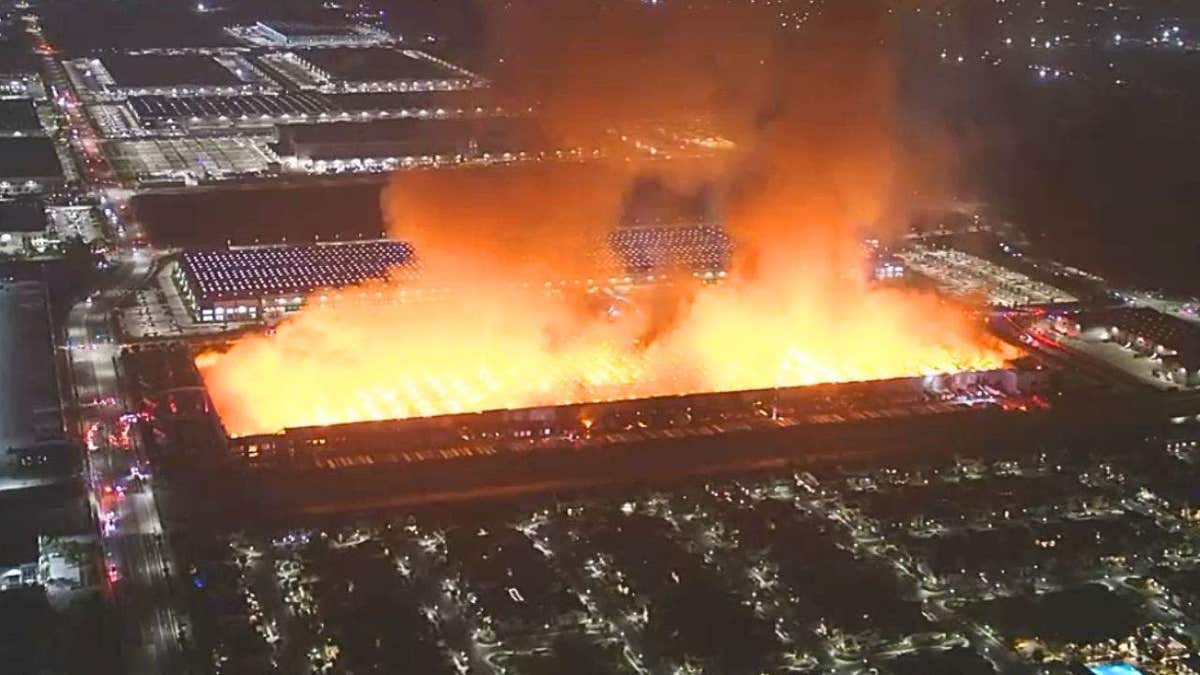 Aerial nighttime representation  of a ample  warehouse afloat   engulfed successful  flames with heavy   fume  rising implicit    an concern   area.