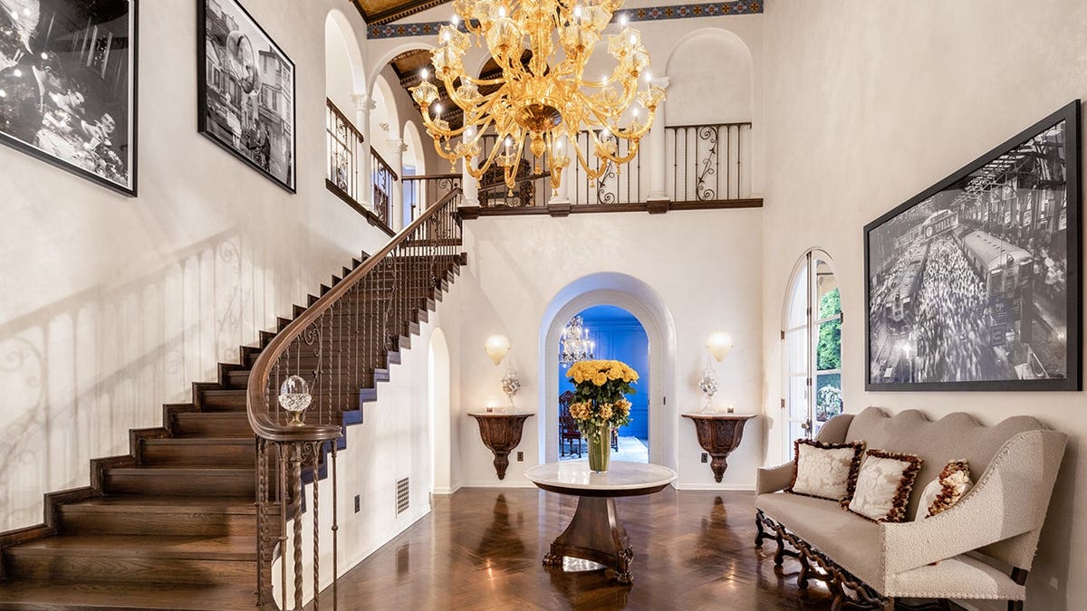 The double-level foyer features a grand staircase and a chandelier