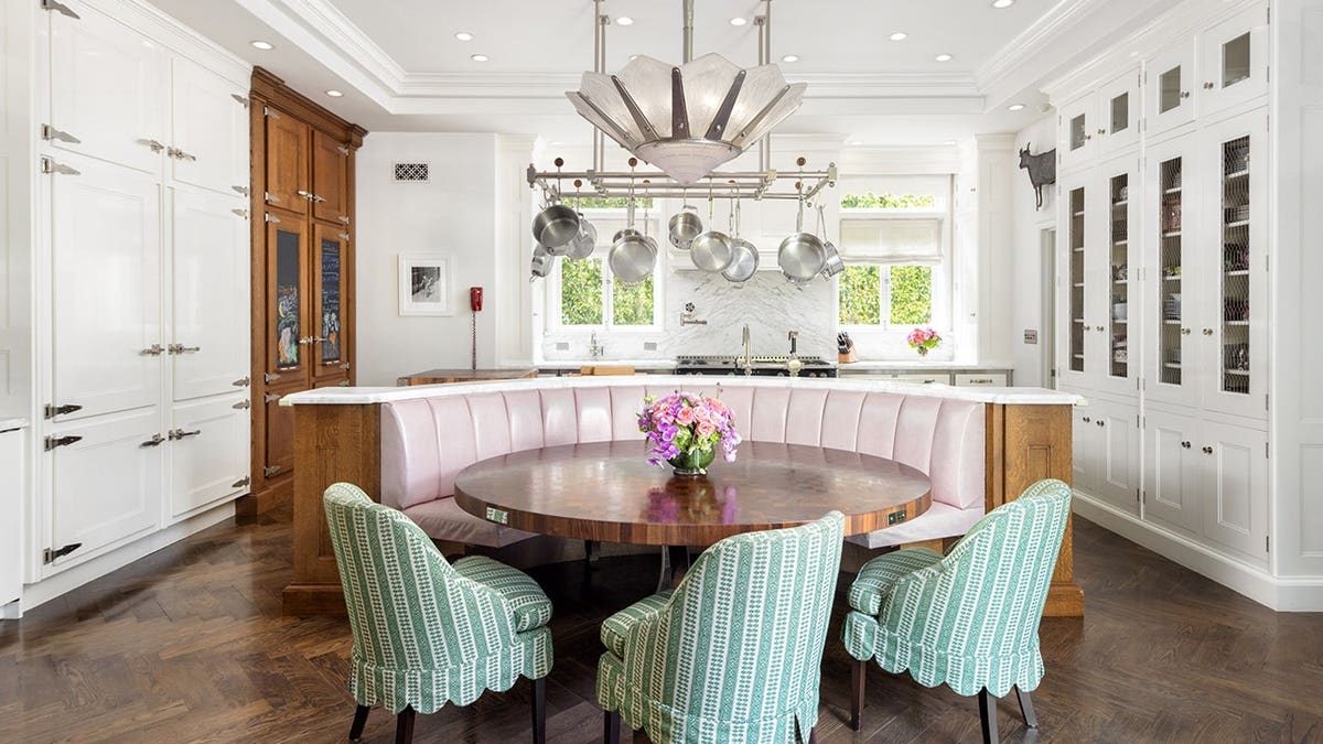 A kitchen with white cabinets and a circular table in the middle