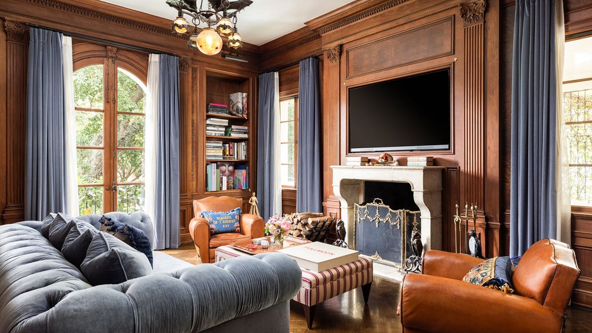 A room with wooden walls, a fireplace and a TV.