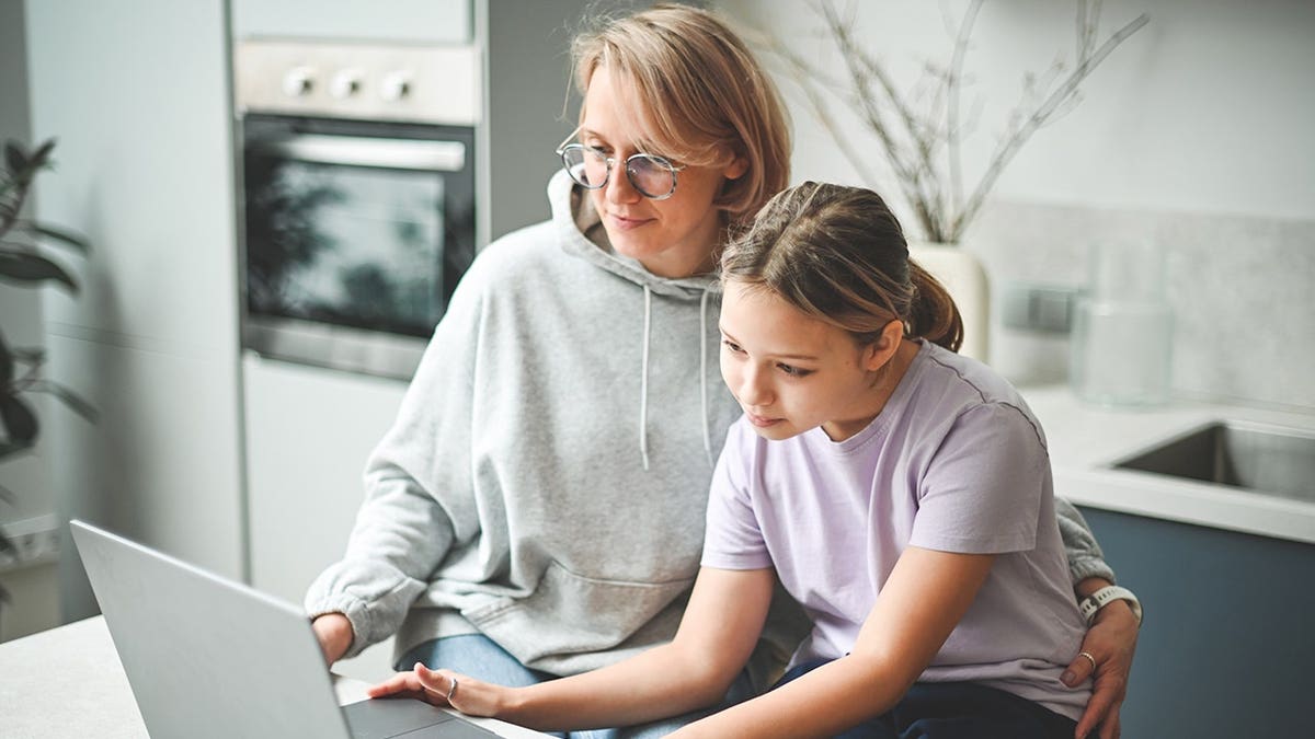 A parent and child look at a laptop