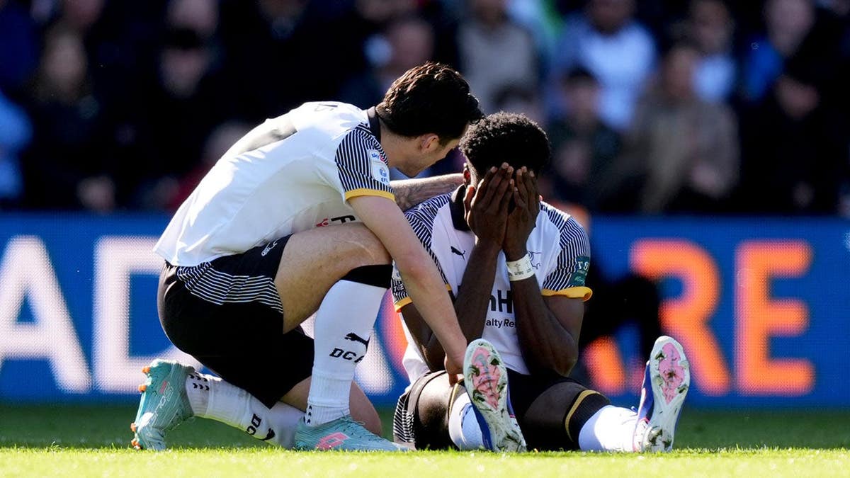 Derby County's Patrick Agyemang holding his head in his hands on the soccer field.