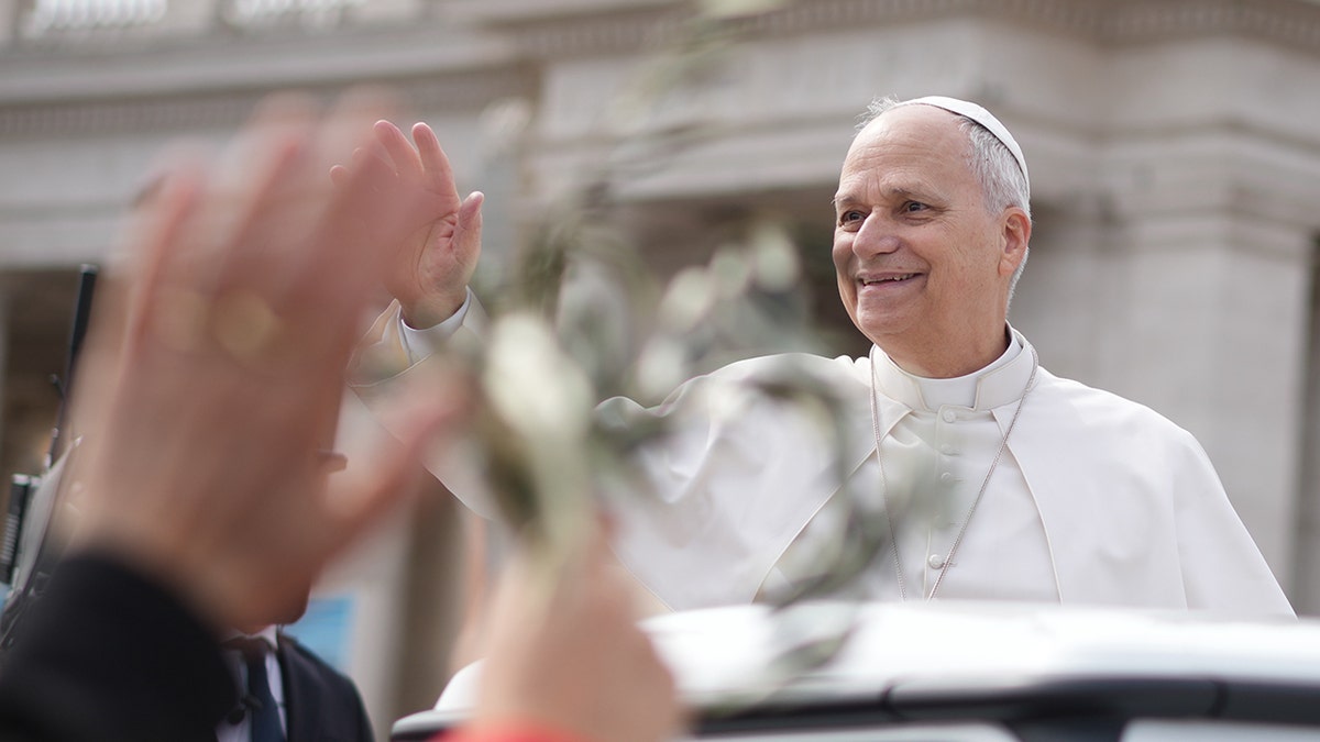 Pope Leo XIV waving while departing from a platform in St. Peter's Square.