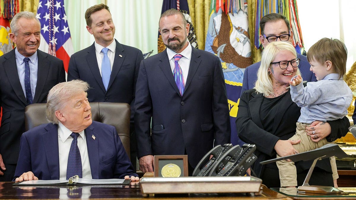 Two-year-old child Travis Smith and his mother Sierra with Trump and others in the in Oval Office