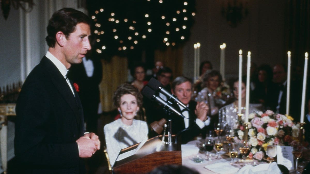 Prince Charles seated with President Ronald Reagan and Nancy Reagan at a dinner.
