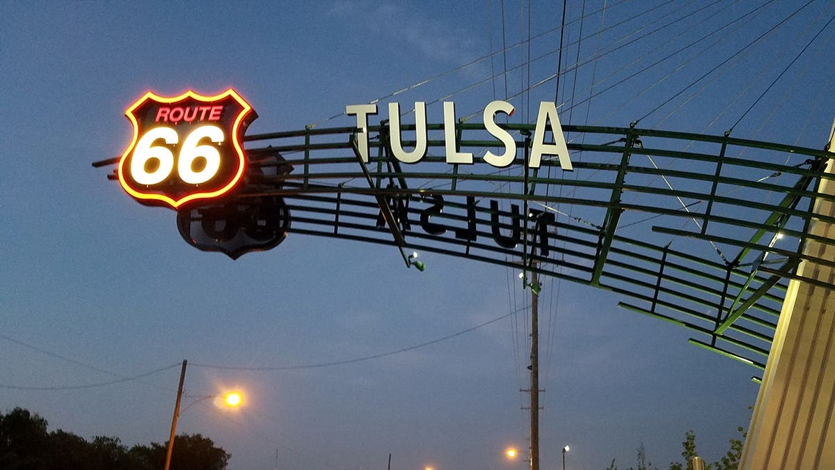 Route 66 Tulsa sign illuminated above highway at night