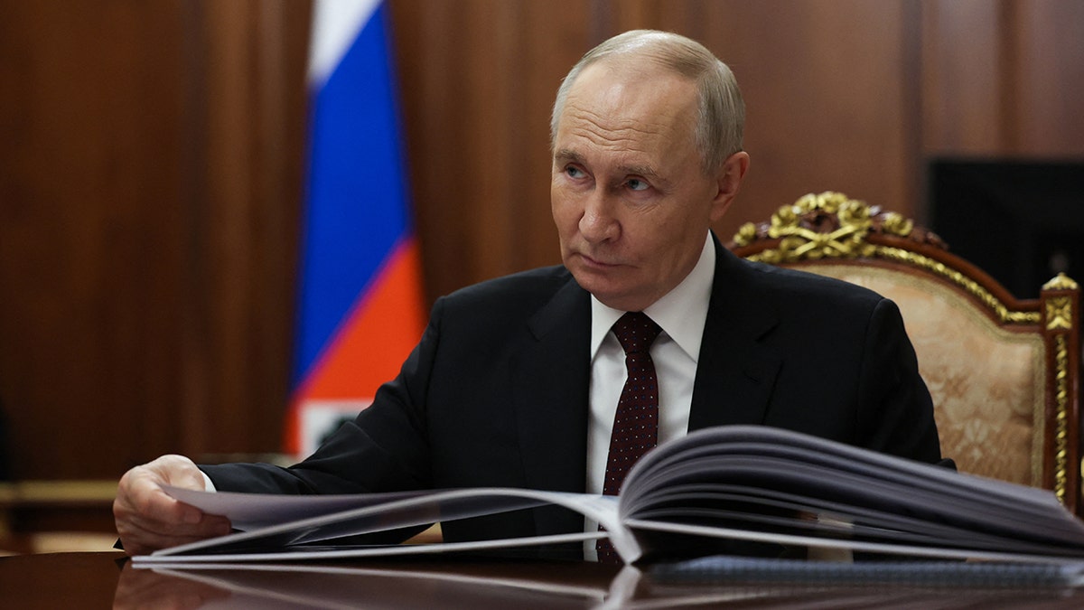 El presidente ruso Vladimir Putin se sienta a una mesa.