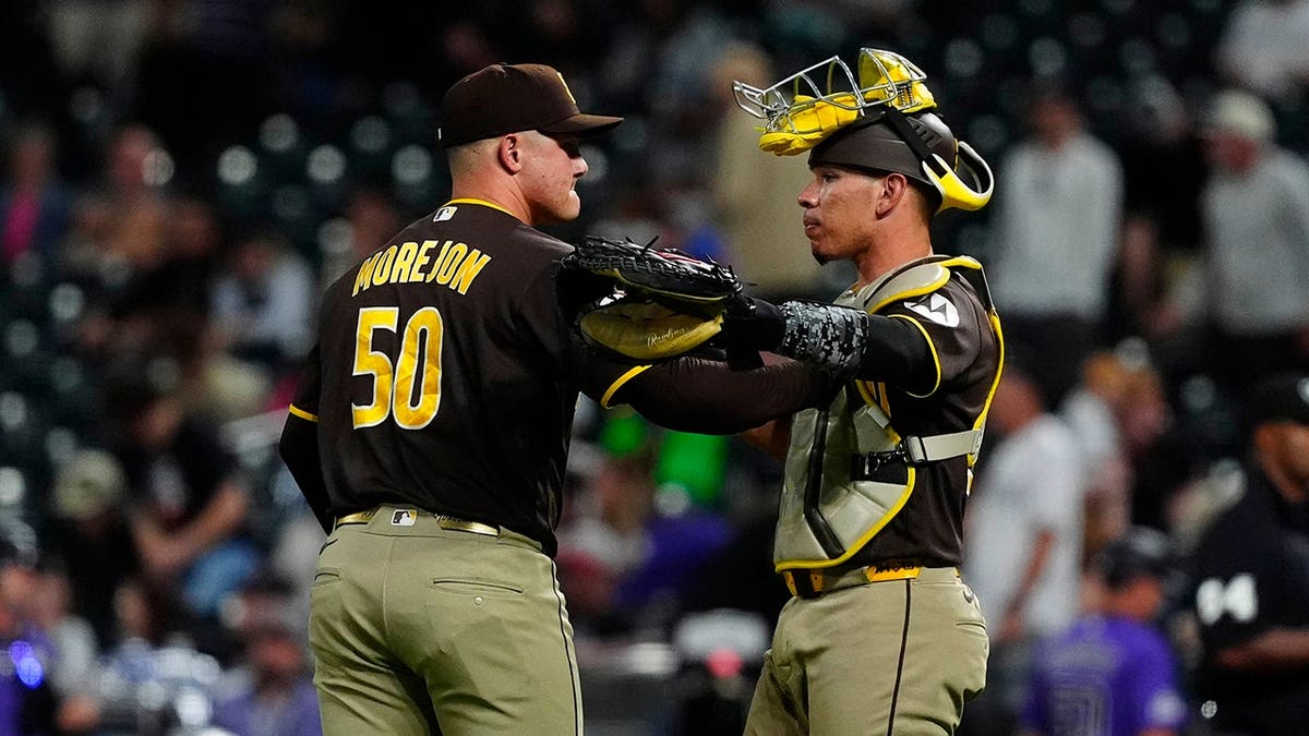 San Diego Padres catcher Freddy Fermin and relief pitcher Adrian Morejon celebrating on the field