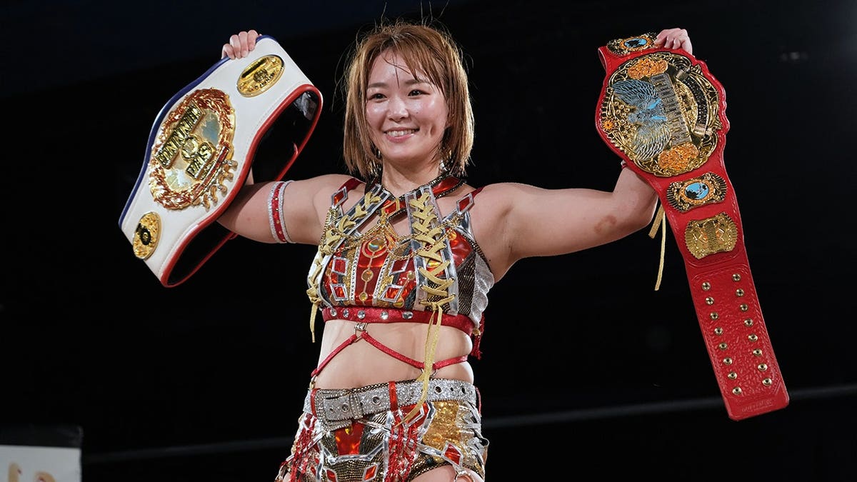 Sareee posing with wrestling belts at Shinjuku FACE in Tokyo
