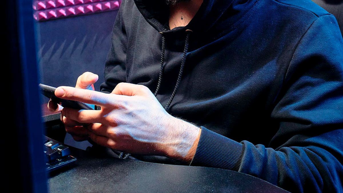 A person in front of a computer using a phone