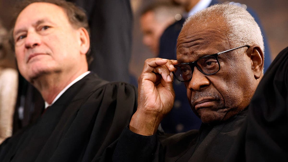 Justices Samuel Alito and Clarence Thomas stand on stage at inauguration ceremony.