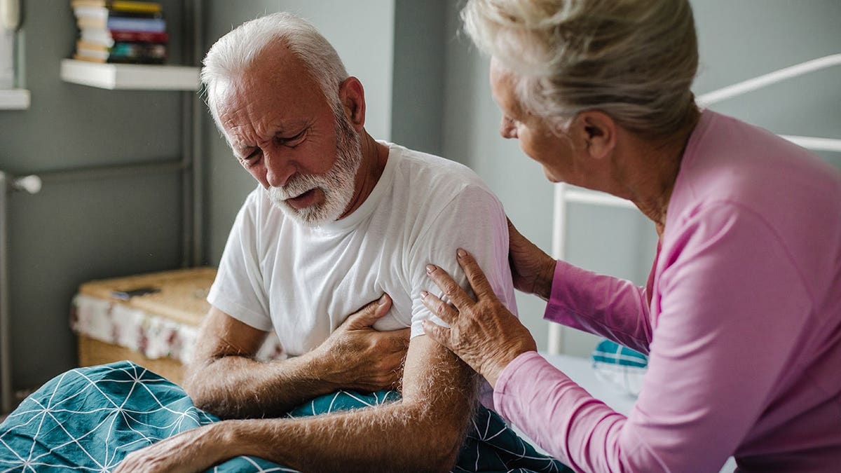 Senior man clutching chest in pain at home
