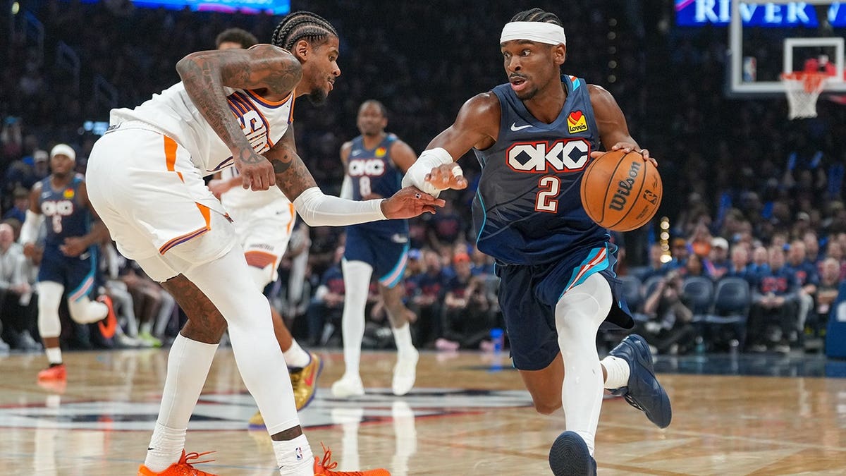 Oklahoma City Thunder guard Shai Gilgeous-Alexander driving past Phoenix Suns guard Jalen Green during a basketball game