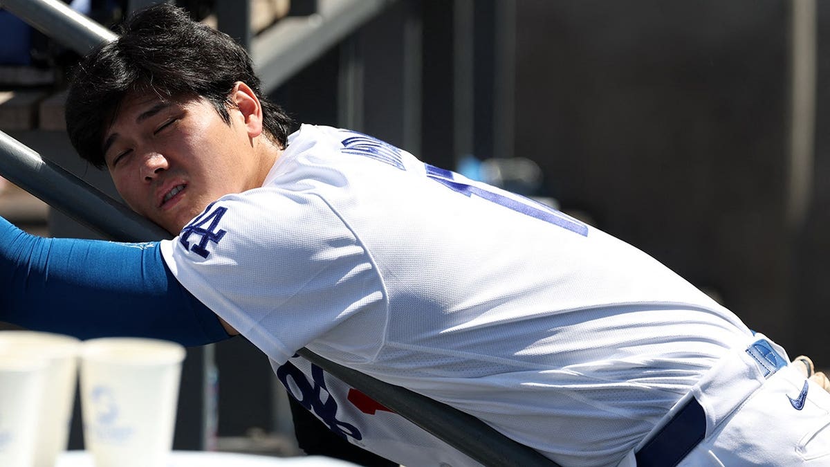Shohei Ohtani leaning on dugout railing during baseball game at Dodger Stadium