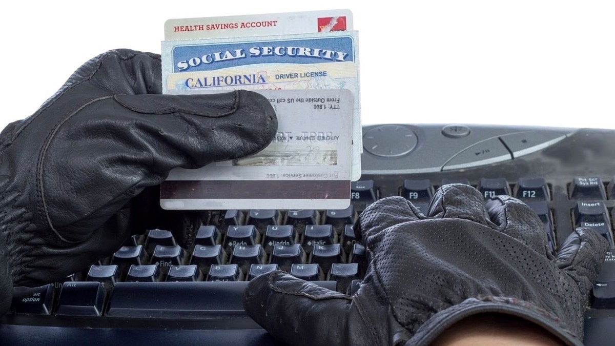 A hacker holding someone's ID cards while typing
