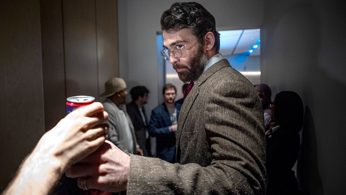 Hasan Piker le da una bebida energética a Mauricio Miranda mientras están junto al escenario.