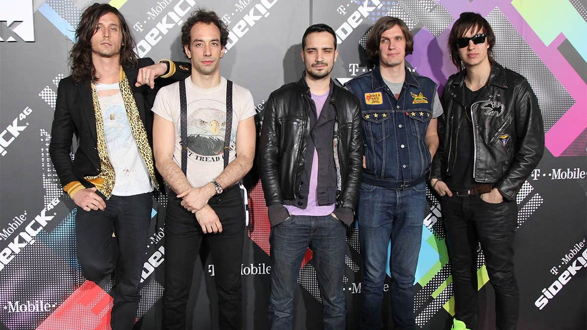 Musicians Nick Valensi, Albert Hammond Jr., Fabrizio Moretti, Nikolai Fraiture and Julian Casablancas of The Strokes standing together at an event.