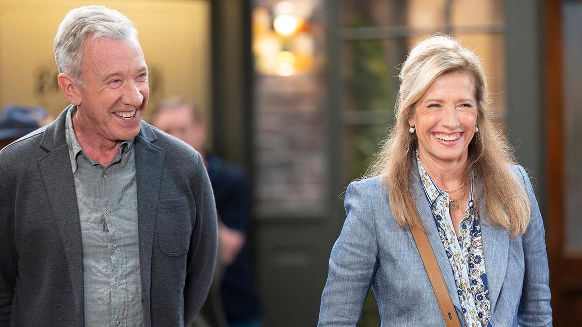 Tim Allen e Nancy Travis sentados juntos em uma televisão