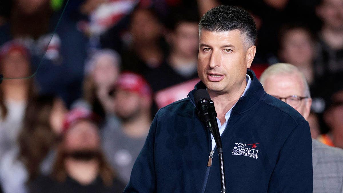 Tom Barrett speaking at Van Andel Arena in Grand Rapids with Donald Trump standing behind him