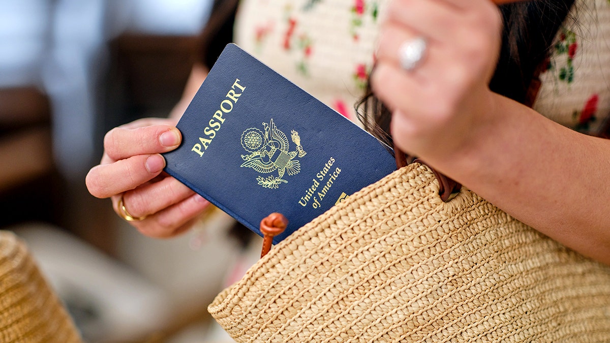 A woman pulls a passport out of her purse.