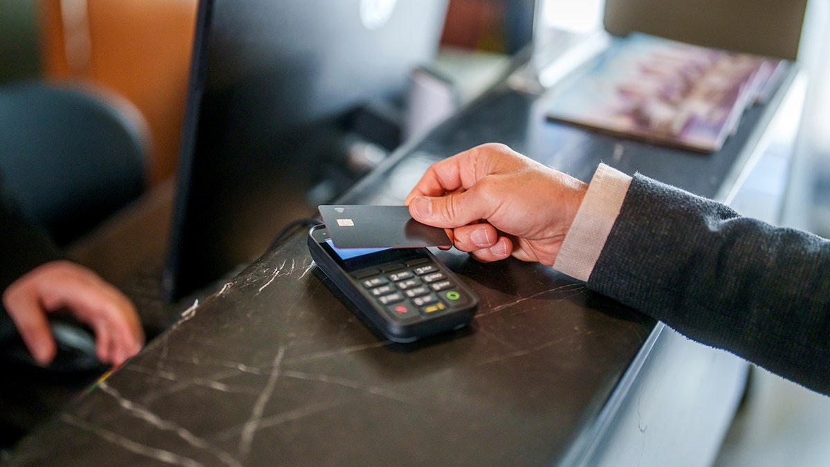 A man pays with a credit card at a hotel desk.