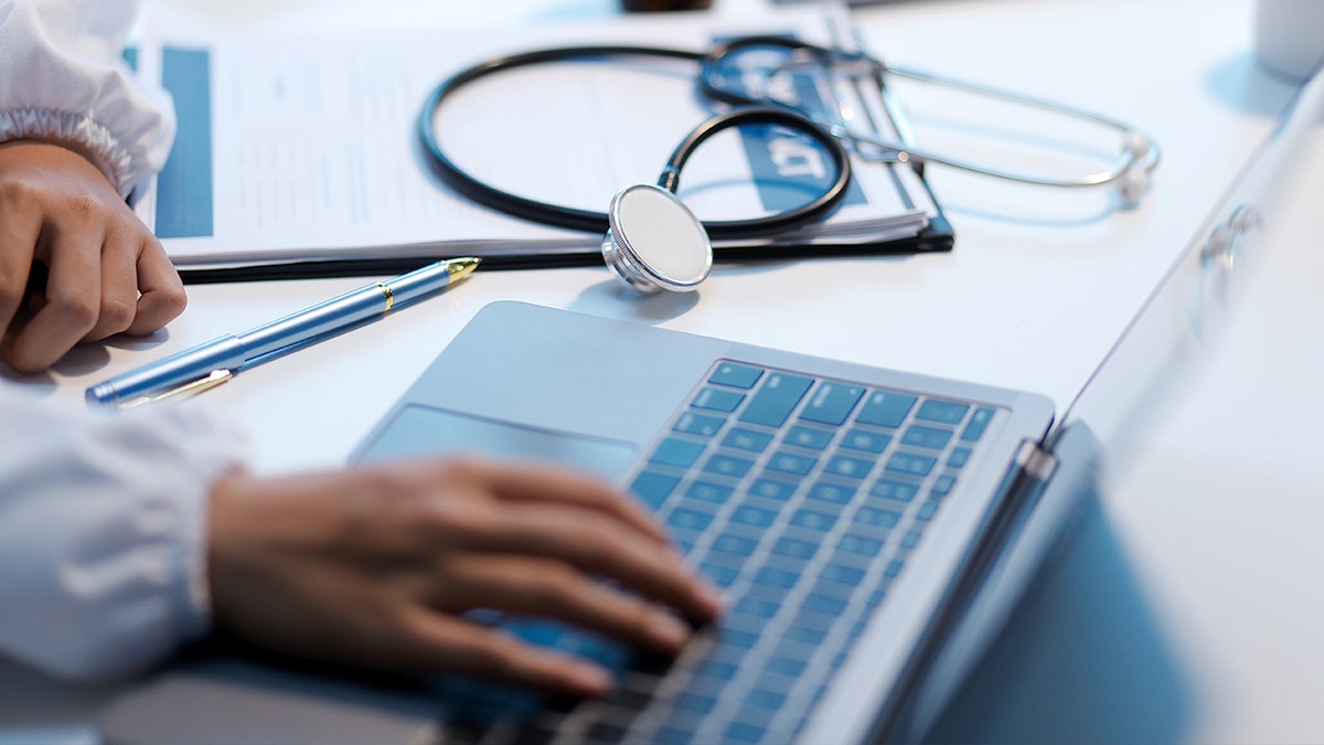 Um estetoscópio fica ao lado de um laptop.