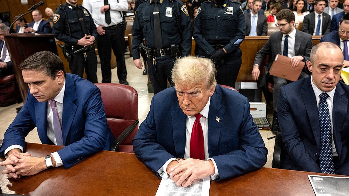 Donald Trump sits in courtroom with attorneys during criminal trial proceedings.
