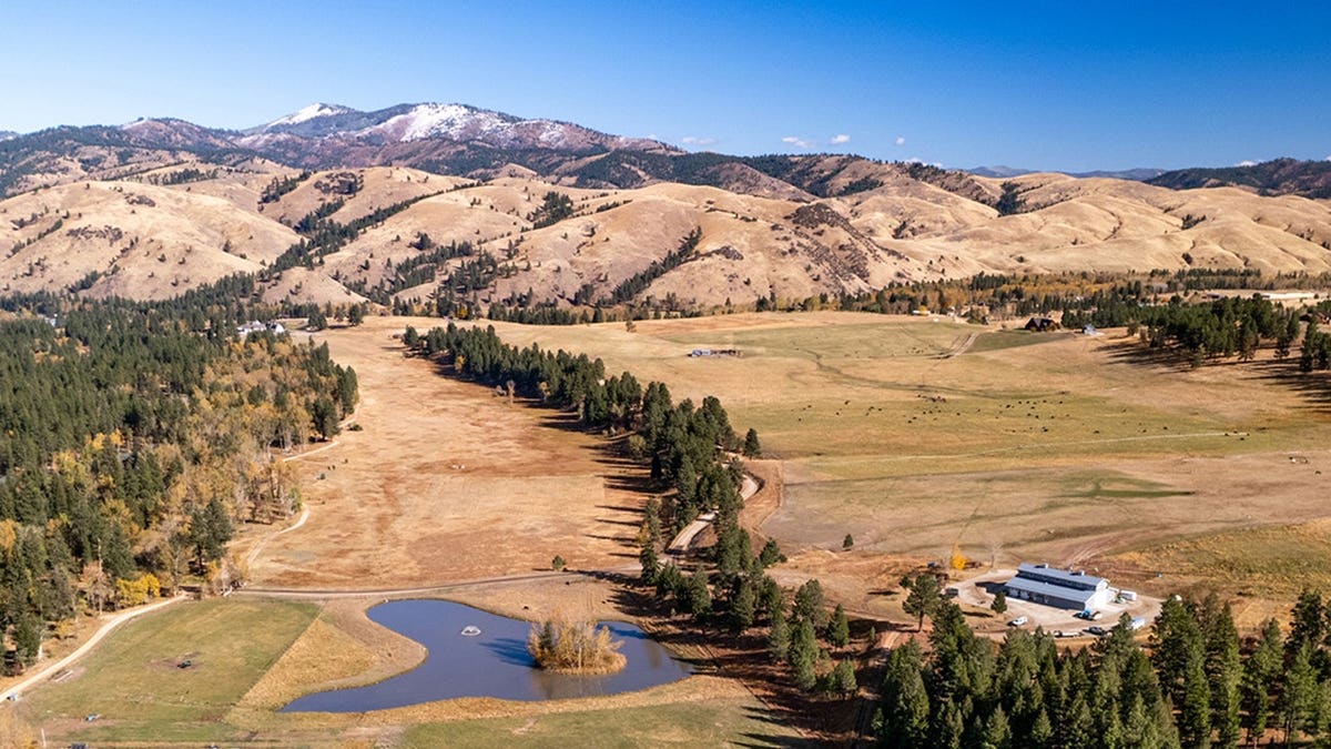Aerial view of Montana ranch with pond, open fields and mountain range
