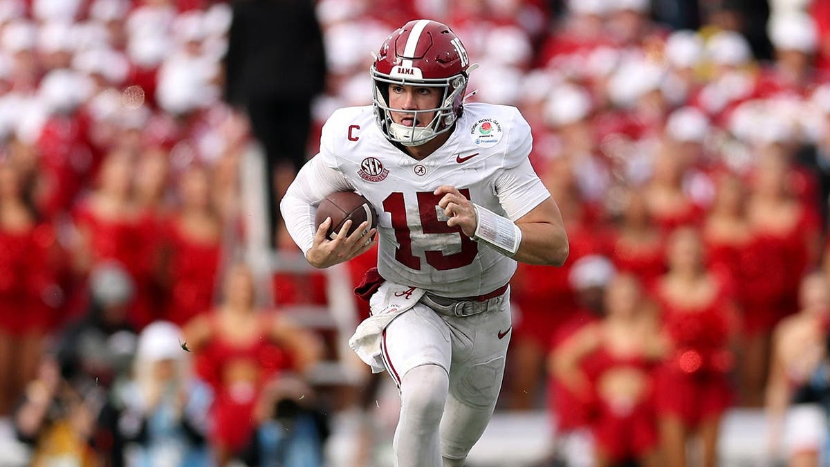 Ty Simpson wearing Alabama Crimson Tide uniform running with football at Rose Bowl Stadium