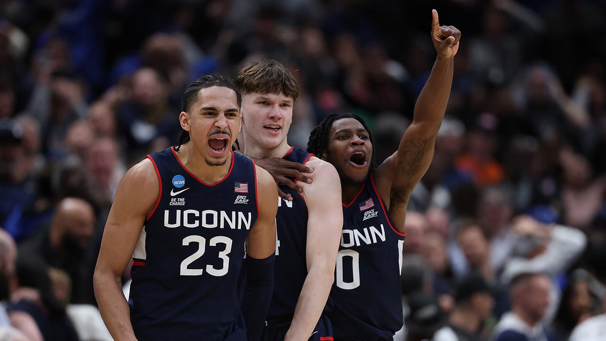 Braylon Mullins celebrates with Jayden Ross and Malachi Smith on basketball court