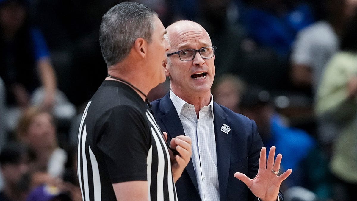 UConn head coach Dan Hurley talking with a referee during a basketball game.