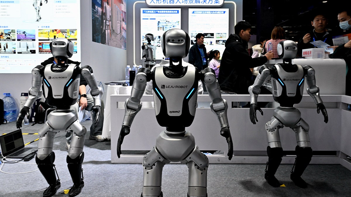 Three robots stand in the middle of a room.
