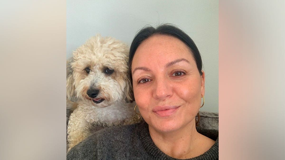 Vickie Doogan sits with her small poochon dog, Dolly, who supported her through breast cancer treatment