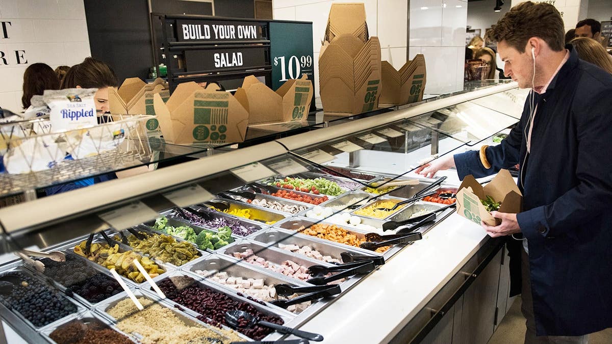 A man makes a salad at the self-serve bar at a Whole Foods Market.