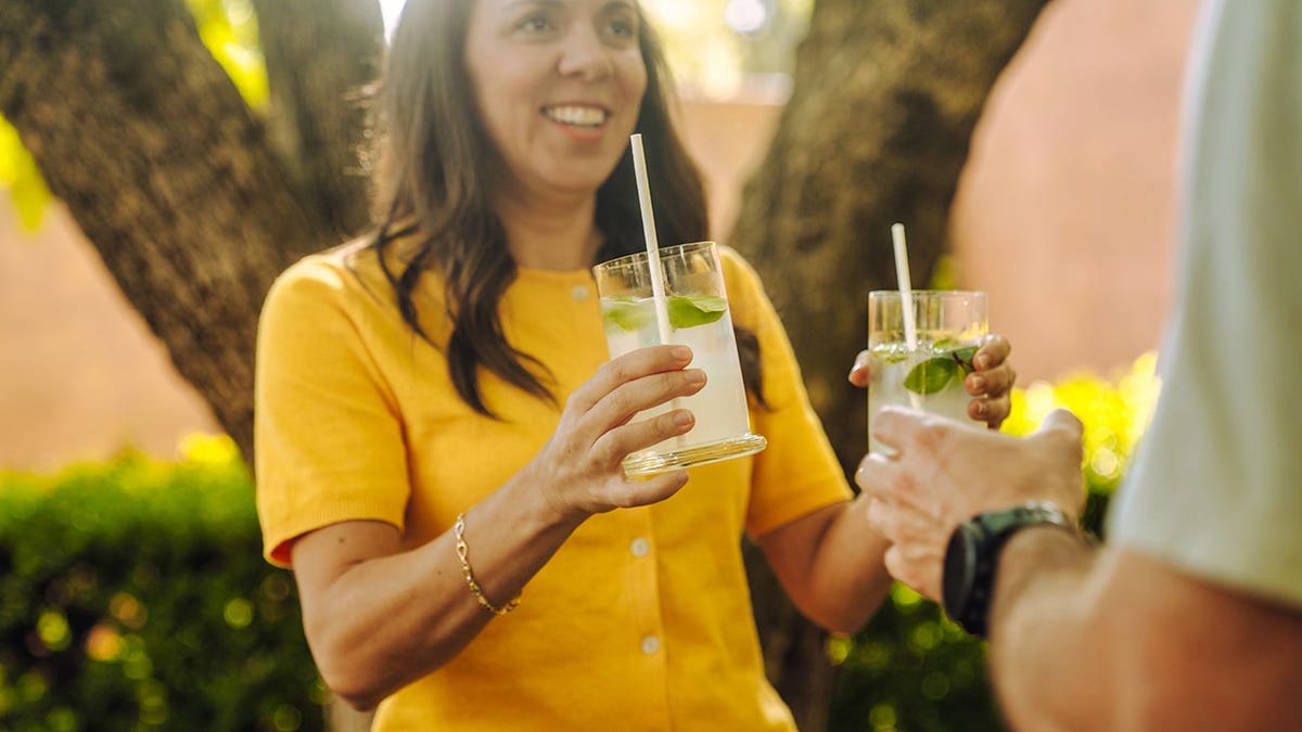 Smiling woman holding glasses at backyard party
