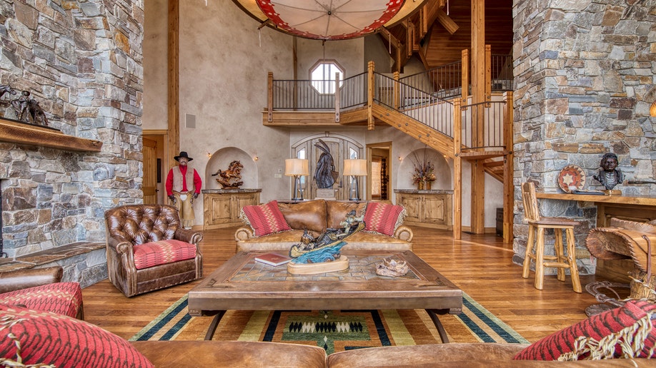 Rustic great room with high ceilings, wood beams and leather furniture