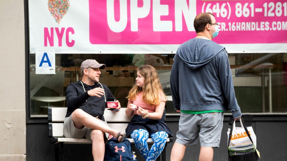 Three people stand outside a 16 Handles store in New York City.
