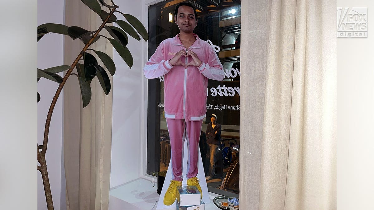 Darshan Magdum holds up a hand heart in a cardboard cutout.